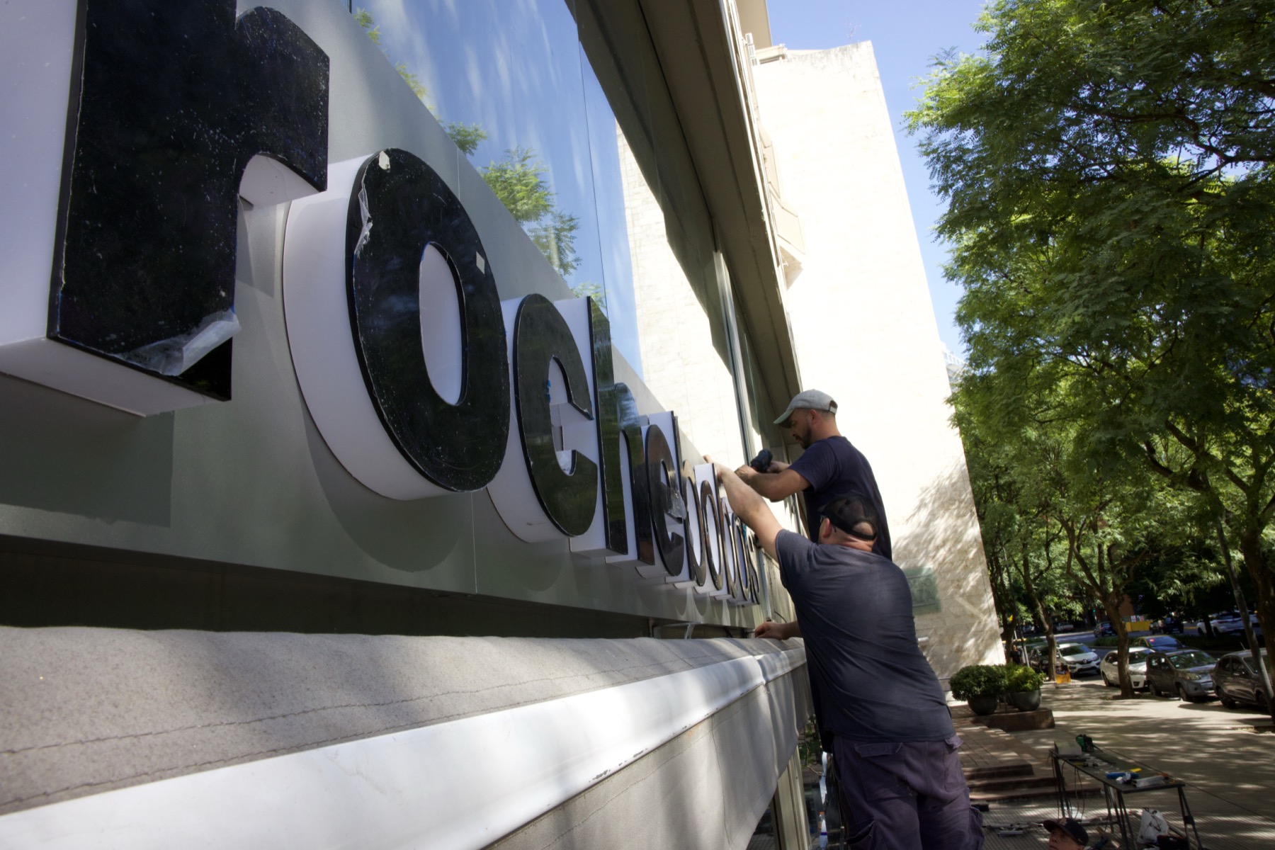 Operarios de HL Publicidad colocando letras corpóreas en una fachada